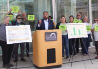 San Jose parks advocates rallied outside City Hall on April 15, 2025 ahead of a City Council discussion over a potential ballot measure benefiting parks funding, with one man standing in front of a podium surrounded by supporters.