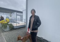 A man stands outside while walking his dog on a leash