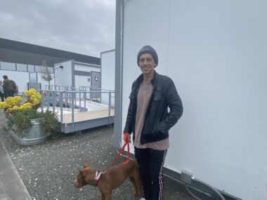 CASAS PEQUEÑAS VIA DEL ORO-- Zachary Plumeau Un hombre está afuera paseando a su perro con correa.