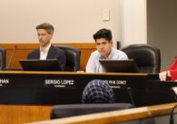 Matt Mahan, a white man with light skin wearing a blue blazer and white button down shirt, sitting beside Sergio Lopez, a tanned Latino man wearing a blue button down, sitting beside Carolyn Gonot, a white woman with reddish hair in a bob wearing a pink blazer, all sitting behind a raised dias