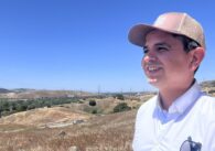 Một người đàn ông đội mũ nhìn ra cánh đồng cỏ