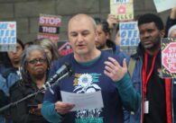 A man standing in front of a podium looking down at a piece of paper in between speech.
