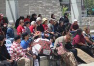A crowd of people sitting outside San Jose City Hall.