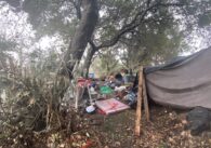 A makeshift tarp tent under a tree near a creek in San Jose, California