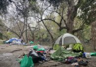 A homeless person's tent and belongings next to a creek