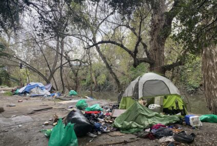A homeless person's tent and belongings next to a creek