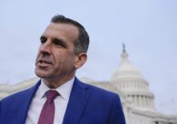A man in a suit stands in front of the Capitol building in Washington, D.C.