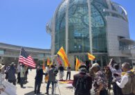 People walking in front of City Hall in San Jose, CA holding American flags and flags of South Vietnam