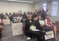 Un grupo de personas con carteles de protesta en una reunión de la junta escolar.