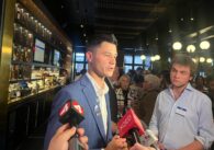 A man in a suit speaking into microphones inside a bar