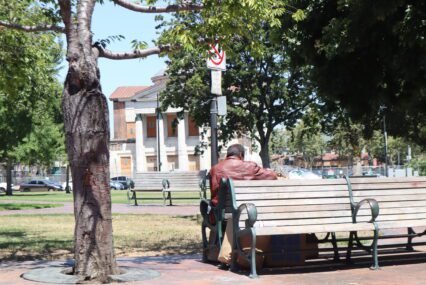 A homeless person sits on a park bench in San Jose, California