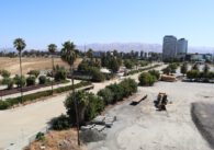 Photo of a large swathe of empty land with some construction equipment and apartment buildings in the background