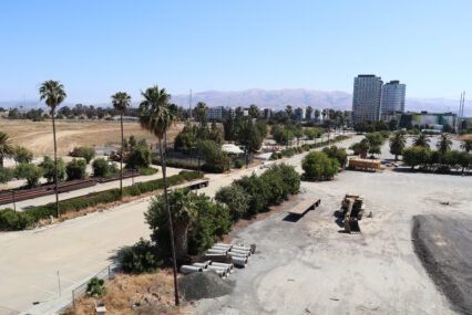 Photo of a large swathe of empty land with some construction equipment and apartment buildings in the background