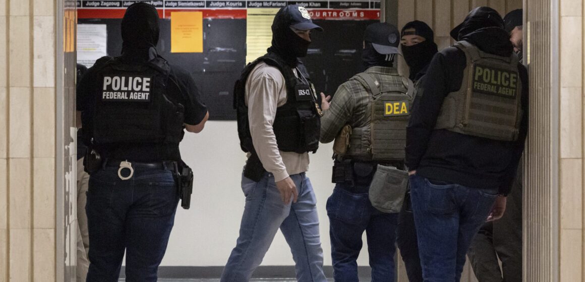 ICE agents wearing masks standing in a hallway