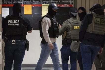ICE agents wearing masks standing in a hallway