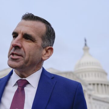 A man in a suit stands in front of the Capitol building in Washington, D.C.