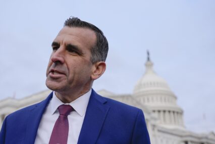A man in a suit stands in front of the Capitol building in Washington, D.C.