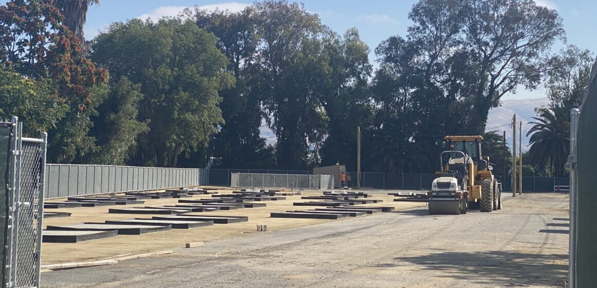 An empty lot with construction vehicles parked in the background