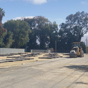 An empty lot with construction vehicles parked in the background