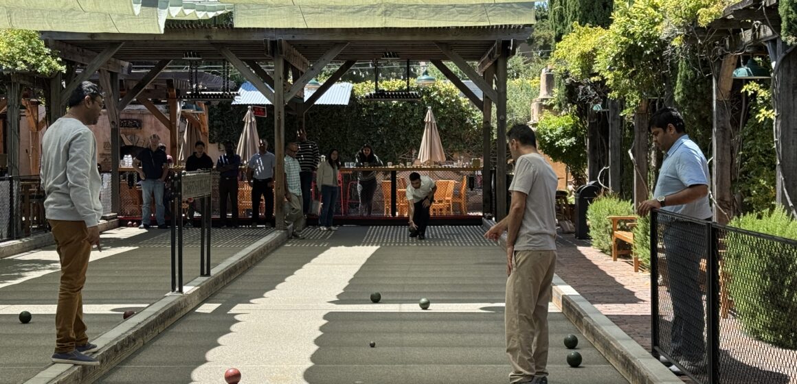 A group of men playing bocce ball on an outdoor court under a covered awning
