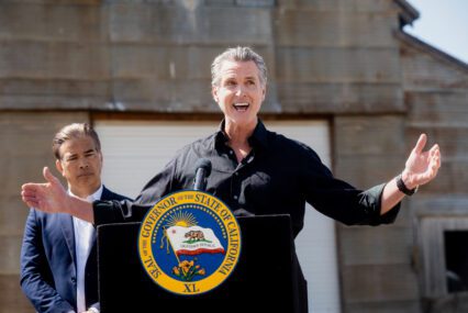 California Governor Gavin Newsom speaking outside behind a podium