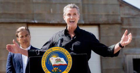California Governor Gavin Newsom speaking outside behind a podium