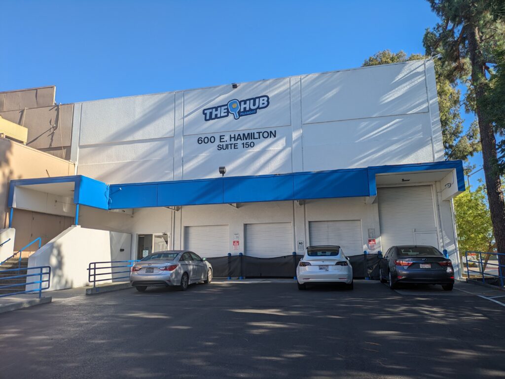 The outside of a white warehouse building with a sign that reads "The Hub"