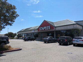 The outside of a Staples, with cars parked in front