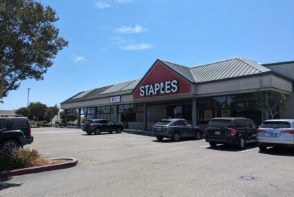 The outside of a Staples, with cars parked in front