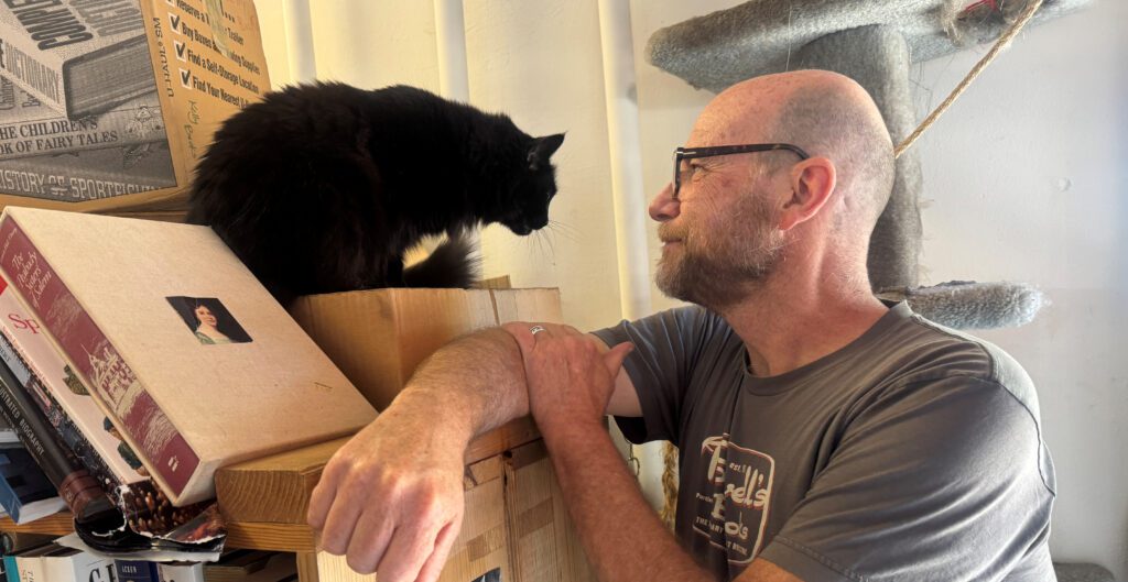 A man in a bookstore looking at a Persian cat