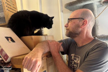 A man in a bookstore looking at a Persian cat
