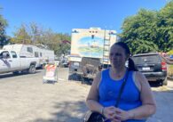 A woman stands in front of RVs and other vehicles in a homeless camp in San Jose, California
