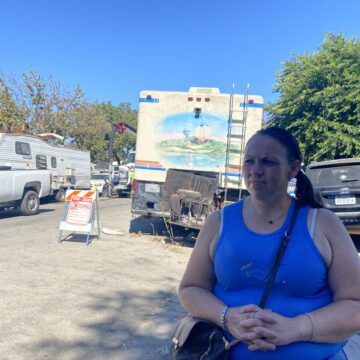 Columbus Park Jennifer Lagone A woman stands in front of RVs and other vehicles in a homeless camp in San Jose, California