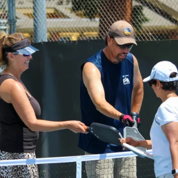 Three people bump rackets on a pickleball court