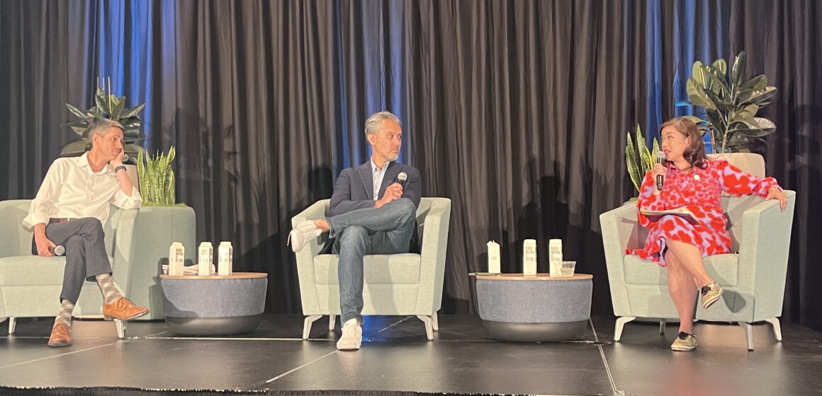 Three people sit in chairs on a stage during a panel discussion