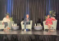 Three people sit in chairs on a stage during a panel discussion