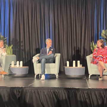 Three people sit in chairs on a stage during a panel discussion
