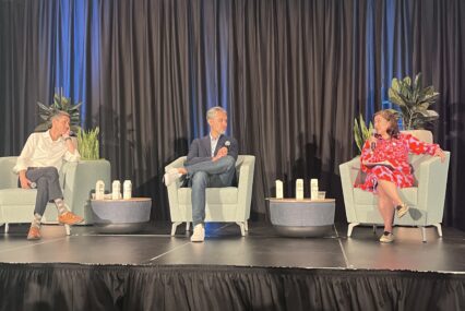 Three people sit in chairs on a stage during a panel discussion