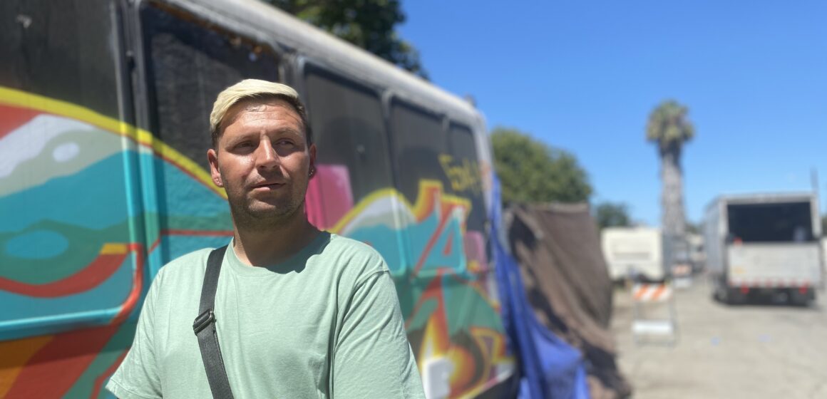 A man stands outside in front of a painted van