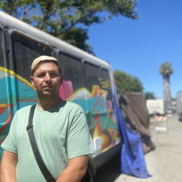 A man stands outside in front of a painted van
