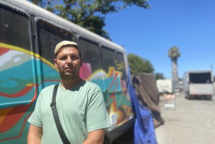 A man stands outside in front of a painted van