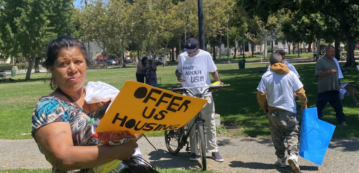 People holding protest signs in a park in downtown San Jose, California