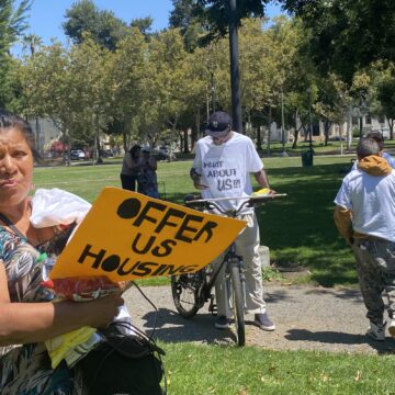 Columbus Park Sweep People holding protest signs in a park in downtown San Jose, California