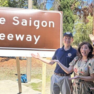 A woman and two men standing in front of a freeway sign
