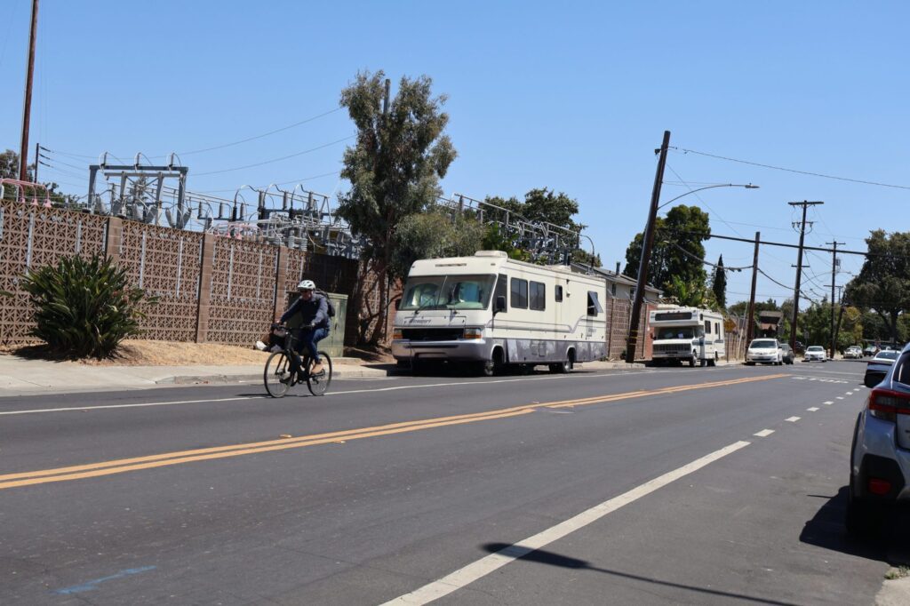 Un ciclista pasa junto a dos casas rodantes habitadas en una calle de Palo Alto, California.