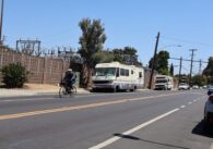 A cyclist rides past two lived-in RVs on a street in Palo Alto, California