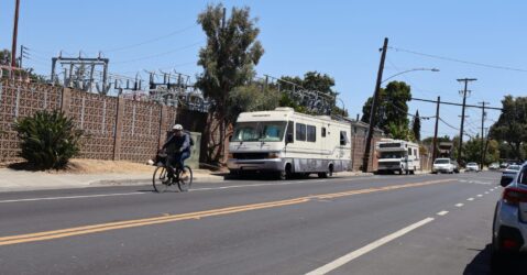 A cyclist rides past two lived-in RVs on a street in Palo Alto, California