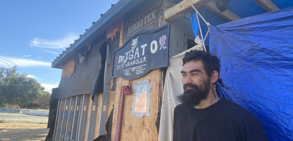 A homeless man stands outside a shack he built to live in at a park in San Jose, California