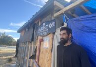 A homeless man stands outside a shack he built to live in at a park in San Jose, California
