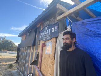 A homeless man stands outside a shack he built to live in at a park in San Jose, California